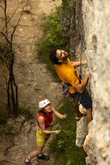 A man and a woman are climbing a rock wall