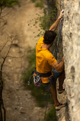 A man in a yellow shirt is climbing a rock wall