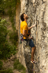 A man in a yellow shirt is climbing a rock wall