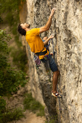 A man in a yellow shirt is climbing a rock wall