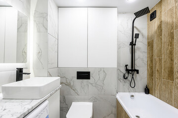 Modern bathroom with white marble tiles, white fixtures, and matte black hardware for a chic,...
