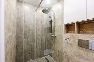 Modern bathroom with a glass shower enclosure, tile walls, and built-in shelving