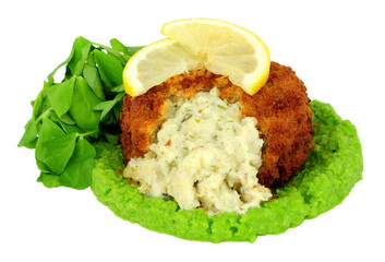 Breadcrumb covered fish cake filled with cod and creamy mashed potato with vivid green pea puree and pea shoot salad leaves isolated on a white background