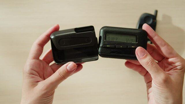 Pager beeper device close up on a desk, retro phone 90s instant communication and connection, sms messaging in the early 80s 90s digital age