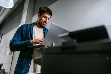 Man working on laptop in modern office space during daylight hours