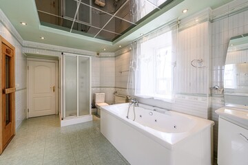 bathroom features a white bathtub, toilet, shower, and vanity. It has tiled walls, floors, and a mirrored ceiling. A window with curtains provides natural light