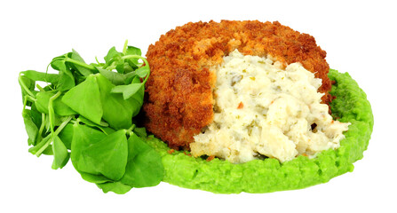 Breadcrumb covered fish cake filled with cod and creamy mashed potato with vivid green pea puree and pea shoot salad leaves isolated on a white background
