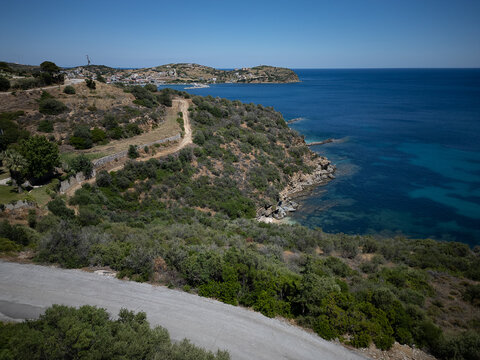 Aerial view of Klimaki Beach, Greece — crystal-clear turquoise waters meeting golden sands and rocky shores, surrounded by lush green hills in serene coastal harmony.
