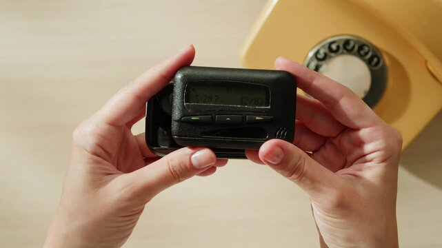 Pager beeper device close up on a desk, retro phone 90s instant communication and connection, sms messaging in the early 80s 90s digital age