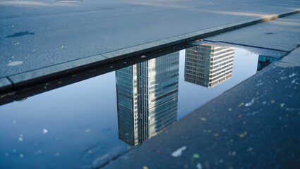 Urban reflection skyscrapers mirrored in puddle