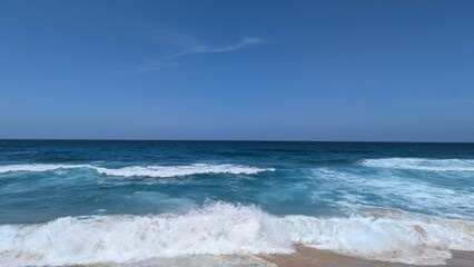 Ocean Waves Crashing on Shoreline Under Clear Blue Sky, Serene Seascape Beauty for Relaxation.