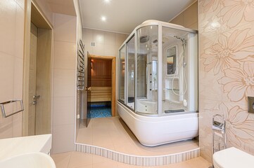 Bright bathroom with a sauna and shower. Floral tile accents add charm