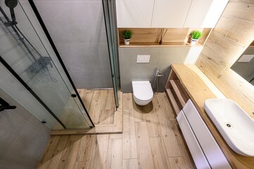 modern bathroom with a glass shower, toilet, wooden accents, and white cabinets