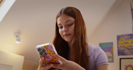 A happy girl uses a mobile phone at home. Close-up of her face