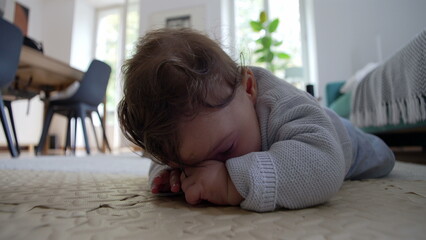 Baby lying on the floor, focused on hands, exploring surroundings, engaged in tactile play, development of fine motor skills, quiet moment of concentration in a home environment