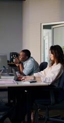 Colleagues work in a modern office. They use laptops while sitting at their desk.
