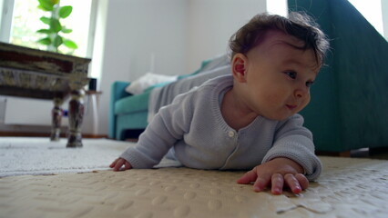 Baby on the floor, pushing up with arms, looking ahead with curiosity, actively exploring surroundings in a living room, early stages of learning to crawl