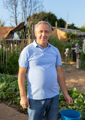 Fototapeta premium Portrait of elderly positive man on his farm on a summer day