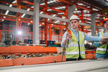 Industrial technicians collaborate in factory, focusing production systems, equipment operation,...