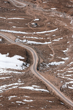 A winding road climbs through the rugged snowy slopes of Ladakh high-altitude mountains, capturing the breathtaking elevation, and dramatic terrain of India trans-Himalayan adventure route