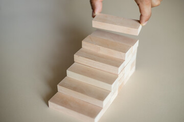 Hand arranging wood block stacking as step stair.