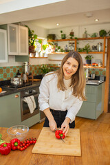 Joyful Cooking Moment: Woman Preparing Fresh Pepper on Wooden Board with Natural Light