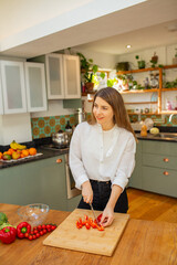 Thoughtful Woman Preparing to Slice Pepper While Standing at Kitchen Counter
