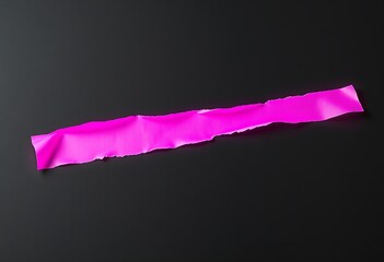 A piece of bright pink torn tape on a black background