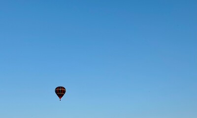 Vibrant hot air balloon floats alone in a clear sky at sunset, creating a serene and dreamy atmosphere with warm evening light.
