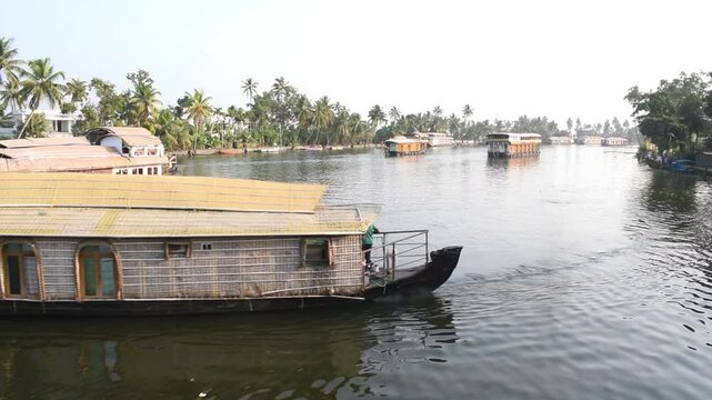 Large traditional houseboat gliding smoothly through the serene backwaters of Alleppey (Alappuzha), Kerala, India.