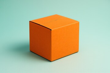 Fototapeta premium Orange cardboard box on an light green surface. Closed container
