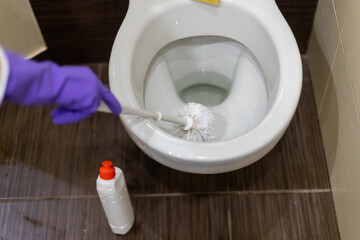 Man hand cleaning toilet with brush
