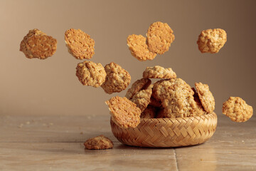Oatmeal cookies in motion on a beige background.