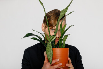 A young smiling man holds in his hands a small flower