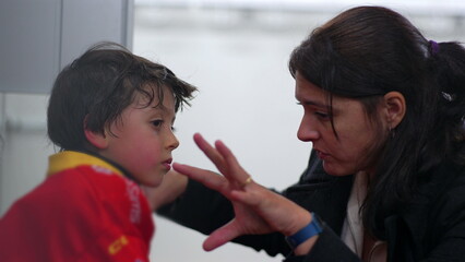 Mother offering advice to young boy after his first experience playing hockey, close conversation in a dressing room setting, discussing the game and offering encouragement