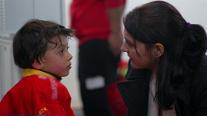 Mother talking to young boy in a coach-like manner after his first hockey trial, dressing room...
