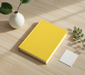 Yellow book mockup with greenery on wooden table