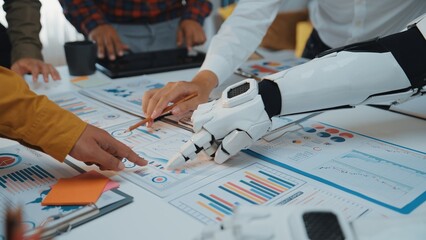 Fototapeta na wymiar A dynamic scene in a modern office where humans and a robot collaborate over data analysis charts, symbolizing teamwork and the future of work integration.Noogenesis