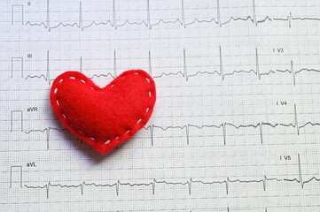 World Heart Rhythm Week concept. Red felt heart against the background of an electrocardiogram.