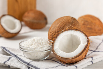 Set of fresh whole and half coconuts and slices on wooden background. Coconut flakes. Vegan. Tropical nut, fruit. Place for text. Copy space.