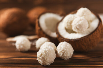 Coconut candies on a wooden background. Candies with chocolate, almonds and delicate butter cream. Coconut flakes. tasty sweets.Tasty ball-shaped chocolate candies.Dessert. Space for text.copy space
