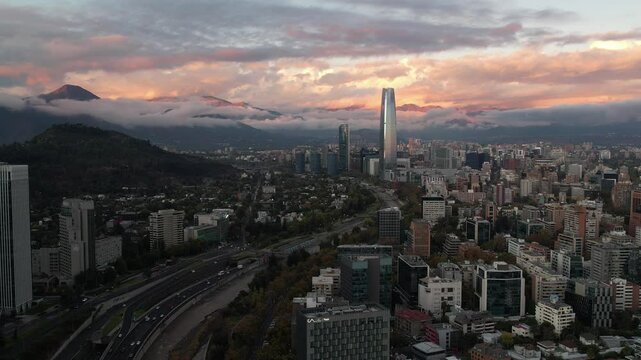 Santiago, Chile &ndash; May 23, 2024: Drone video flying over Santiago toward Costanera Center at sunset, with low clouds over the Andes and city skyline in soft evening light.