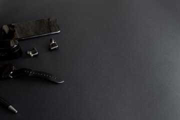 black pen, black smart watch, smartphone, wireless headphones on dark background