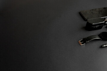 black pen, black smart watch, smartphone, wireless headphones on dark background