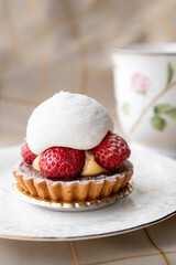 A Tart with strawberries and cream on a white plate