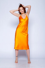 Portrait of attractive girl in orange dress in the studio