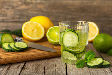 Cucumber water with lemon, lime and mint on a wooden table. Water infused with sliced...