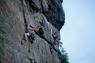 A girl climbs a rock. Woman engaged in extreme sport.