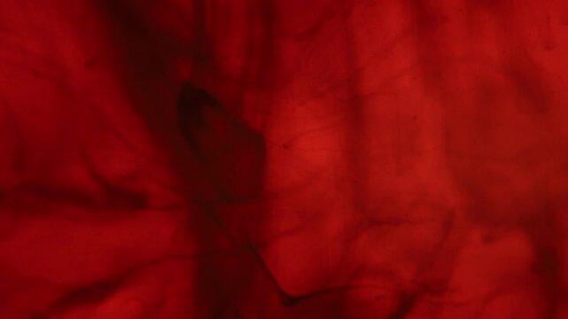 Black drops in the red liquid, abstraction, dark horror background 