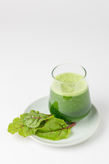 Freshly squeezed juice or organic smoothie in a glass with chard leaves on plate  on white background  isolated